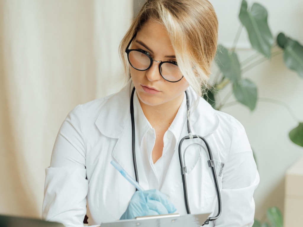 Clinician documenting notes — the manual workflow longevity practices still rely on